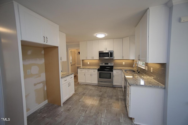 kitchen featuring dark wood-style floors, decorative backsplash, appliances with stainless steel finishes, and a sink