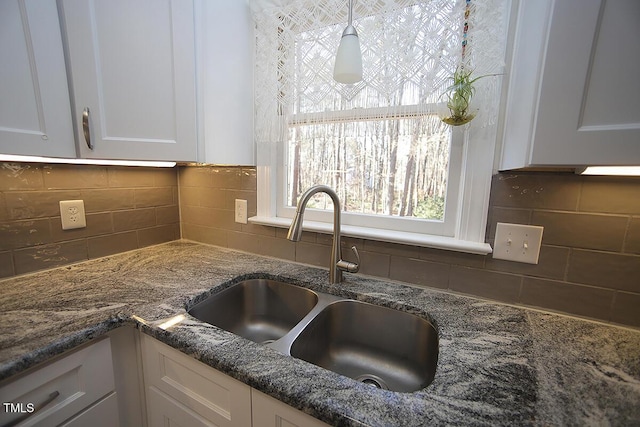 room details featuring a sink, stone counters, backsplash, and white cabinets