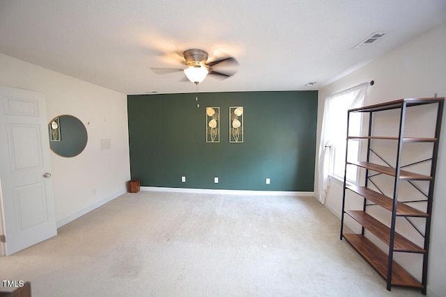 unfurnished room featuring visible vents, light carpet, baseboards, and ceiling fan