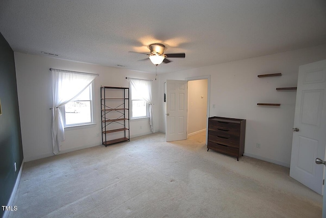 unfurnished bedroom with visible vents, a ceiling fan, a textured ceiling, baseboards, and light colored carpet