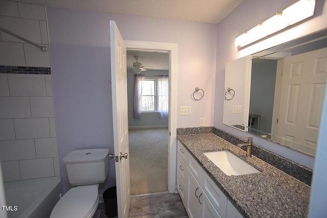 bathroom with vanity, toilet, a ceiling fan, and a textured ceiling