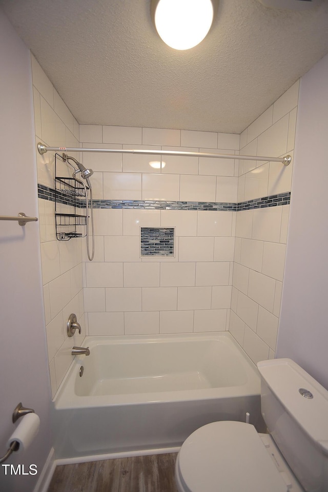 bathroom with a textured ceiling, toilet, shower / bathing tub combination, and wood finished floors