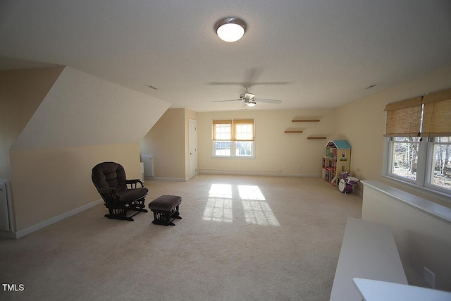 living area featuring vaulted ceiling, carpet flooring, a ceiling fan, and baseboards