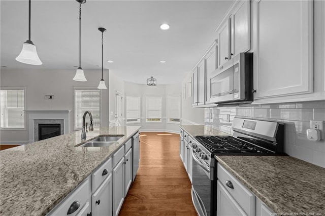 kitchen with a high end fireplace, backsplash, dark wood-type flooring, appliances with stainless steel finishes, and a sink