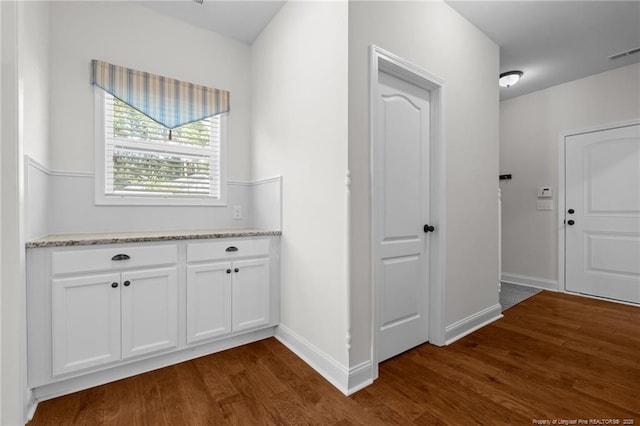 hallway featuring dark wood-style floors, visible vents, and baseboards