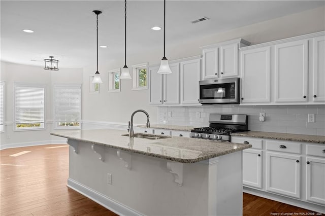 kitchen with a sink, stainless steel appliances, visible vents, and white cabinets