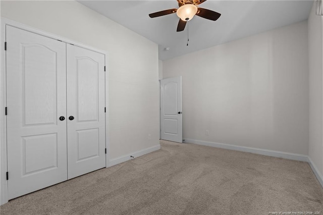 unfurnished bedroom featuring a closet, light carpet, baseboards, and a ceiling fan