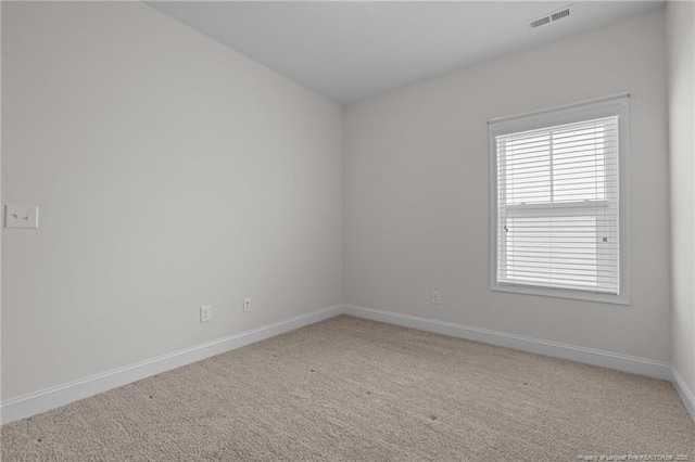 empty room featuring visible vents, light carpet, and baseboards