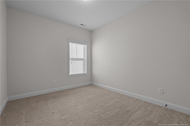 carpeted spare room with visible vents and baseboards