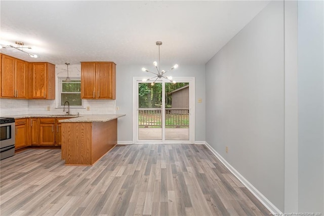 kitchen featuring baseboards, light wood-type flooring, decorative backsplash, brown cabinets, and a peninsula