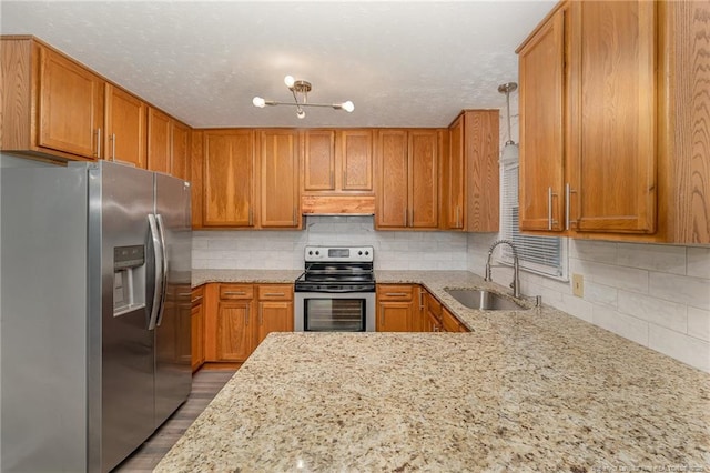 kitchen featuring light stone countertops, decorative backsplash, appliances with stainless steel finishes, custom exhaust hood, and a sink