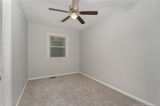 unfurnished room with visible vents, carpet floors, baseboards, and a ceiling fan