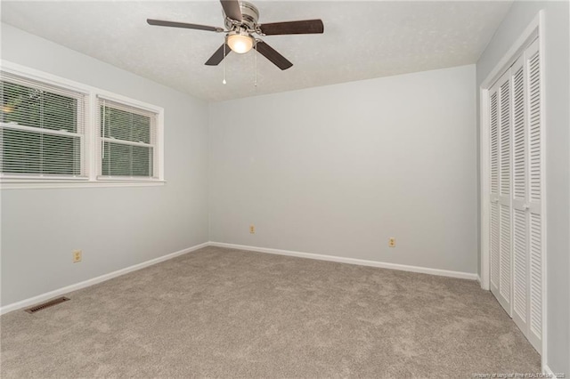 unfurnished bedroom featuring visible vents, ceiling fan, baseboards, carpet floors, and a closet