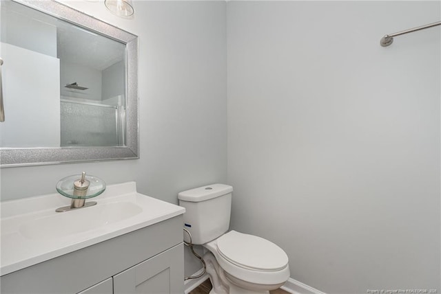 full bathroom featuring vanity, toilet, a shower, and baseboards