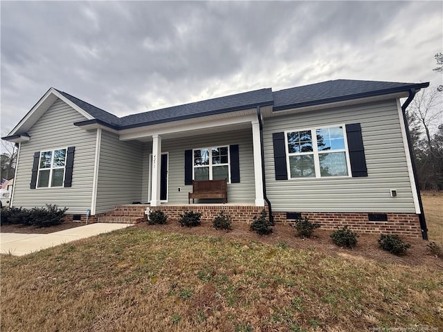 view of front of house with a shingled roof, a porch, a front lawn, and crawl space