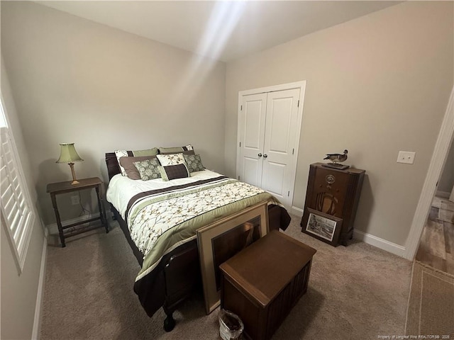 carpeted bedroom with a closet and baseboards