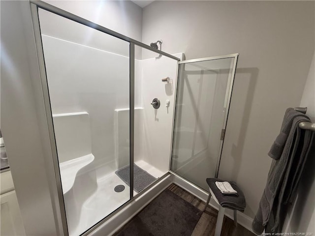 bathroom with a shower stall and wood finished floors