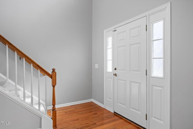 entrance foyer with baseboards, wood finished floors, and stairs