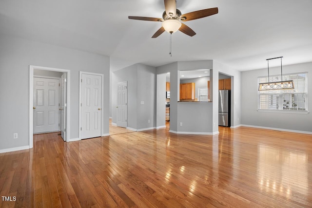 unfurnished living room featuring a ceiling fan, light wood-type flooring, and baseboards