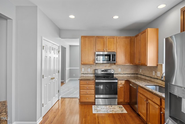 kitchen with tasteful backsplash, stainless steel appliances, dark stone counters, and a sink