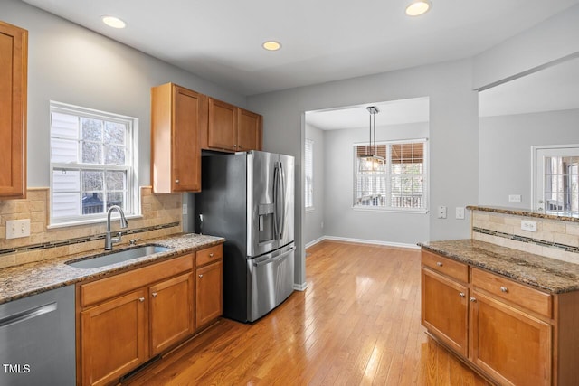 kitchen featuring a wealth of natural light, stone counters, stainless steel appliances, and a sink