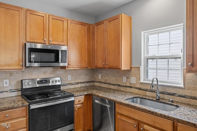 kitchen with a sink, dark stone countertops, and stainless steel appliances