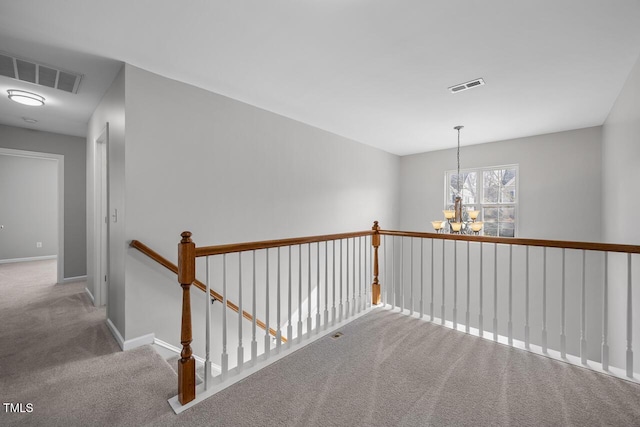 hallway with visible vents, a chandelier, and carpet flooring