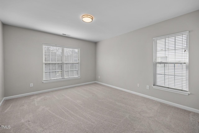 empty room with visible vents, carpet, and baseboards