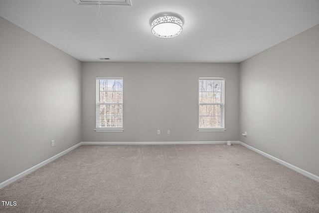 spare room featuring visible vents, carpet flooring, attic access, and baseboards