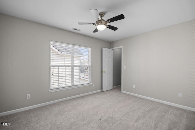 spare room with visible vents, light carpet, baseboards, and a ceiling fan