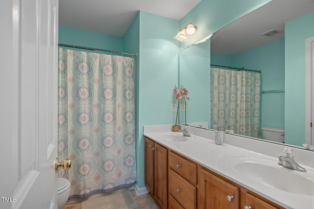 full bathroom featuring a sink, toilet, and double vanity