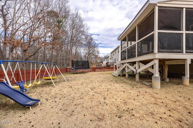 view of yard with a playground, a trampoline, fence, stairway, and a sunroom