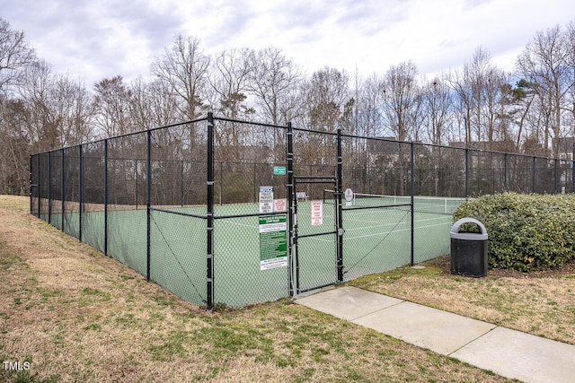 view of sport court with fence, a yard, and a gate