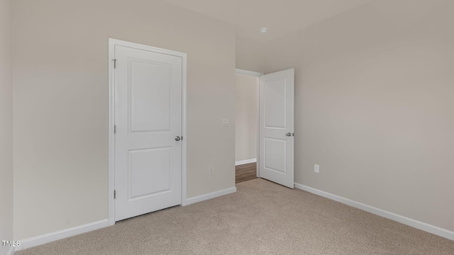 unfurnished bedroom with baseboards and light carpet