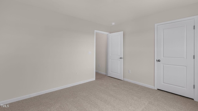 unfurnished room featuring baseboards and light colored carpet