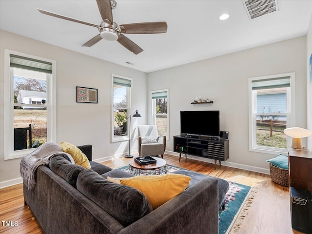 living area featuring visible vents, baseboards, a ceiling fan, and light wood finished floors