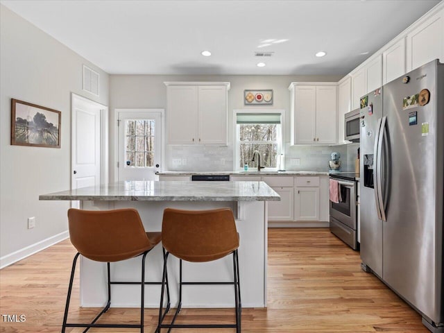 kitchen featuring visible vents, plenty of natural light, appliances with stainless steel finishes, and a breakfast bar