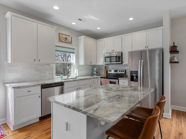 kitchen with white cabinets, a breakfast bar area, visible vents, and stainless steel appliances