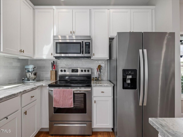 kitchen with white cabinetry, light stone counters, tasteful backsplash, and appliances with stainless steel finishes