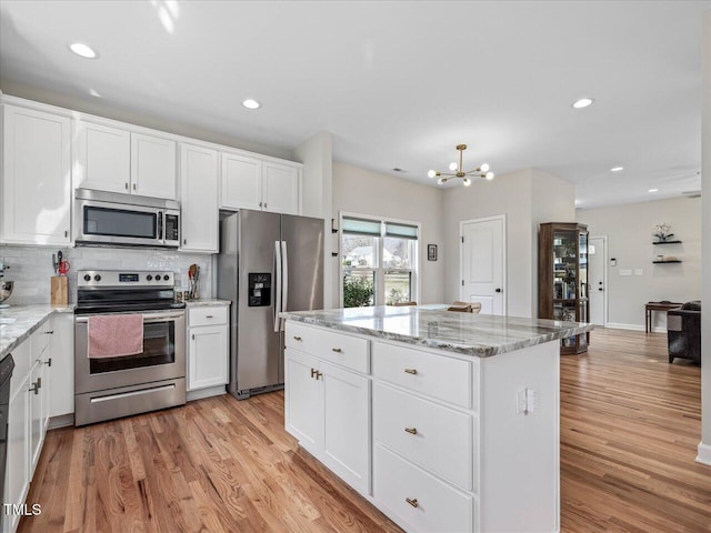 kitchen with decorative backsplash, light wood-style floors, appliances with stainless steel finishes, and a center island