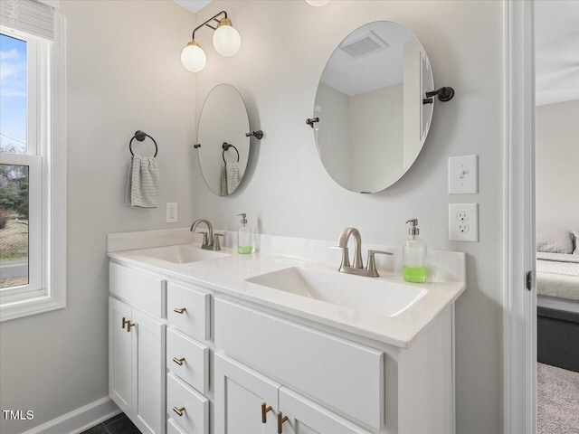 ensuite bathroom with a sink, connected bathroom, baseboards, and double vanity