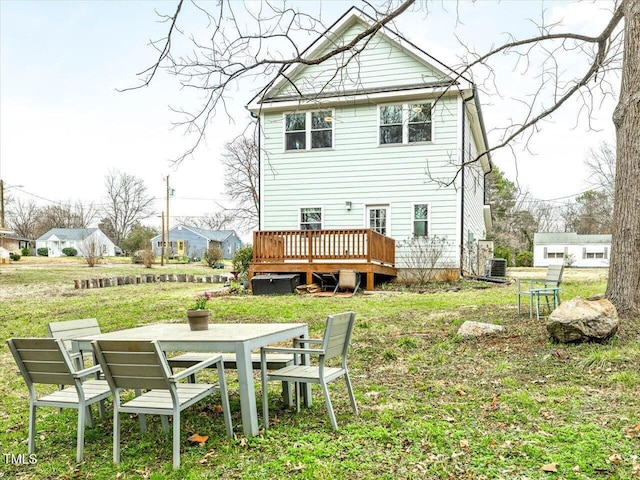 rear view of property featuring a deck, outdoor dining space, a lawn, and central AC