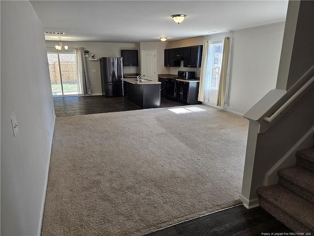 kitchen featuring dark colored carpet, open floor plan, a sink, and freestanding refrigerator