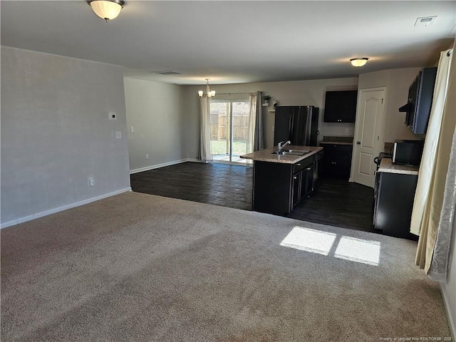 kitchen featuring light countertops, dark cabinetry, dark colored carpet, and a sink