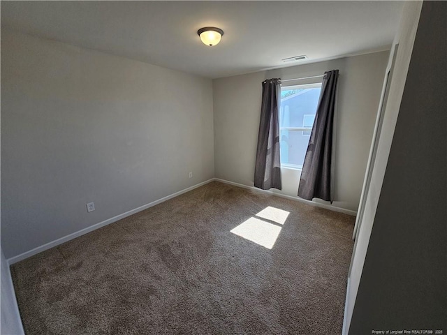 carpeted spare room featuring visible vents and baseboards