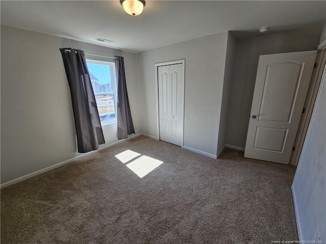 unfurnished bedroom featuring visible vents, baseboards, carpet, and a closet