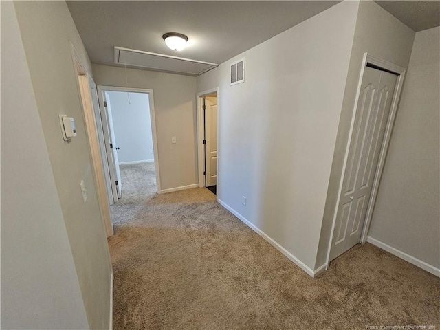 hallway featuring visible vents, carpet flooring, attic access, and baseboards