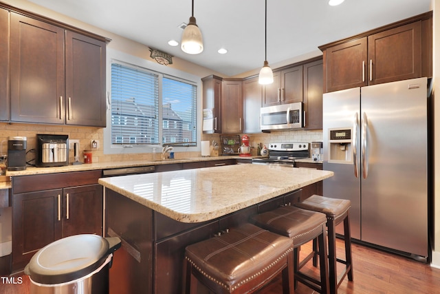 kitchen featuring light stone counters, backsplash, appliances with stainless steel finishes, and a sink