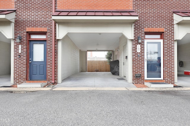 doorway to property with metal roof, brick siding, and a standing seam roof