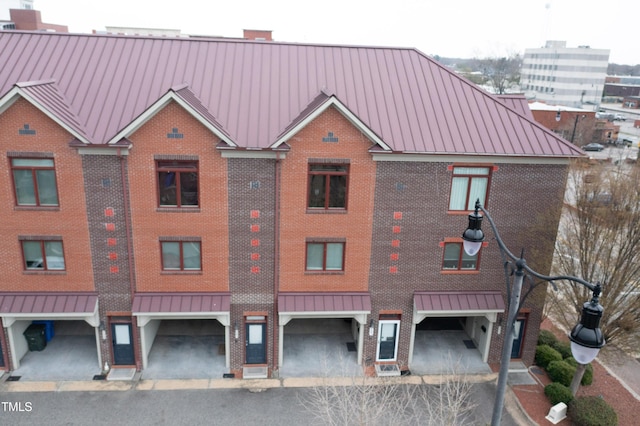 view of front facade with brick siding, a chimney, a standing seam roof, and metal roof